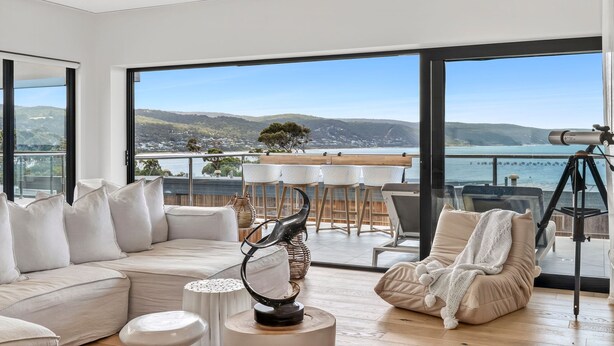 A modern living room with a large window overlooking a scenic view, a telescope, and a cozy seating area. - 9 Oceania (Lorne)