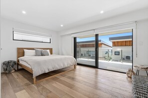 A bedroom with a bed, a large window, and a view of buildings outside. - 9 Oceania (Lorne)