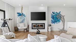 A modern living room with a fireplace, white furniture, and abstract art. - 9 Oceania (Lorne)