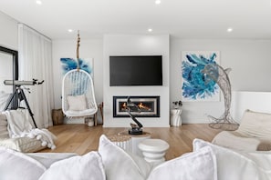 A modern living room with a fireplace, white furniture, and abstract art. - 9 Oceania (Lorne)
