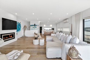 A modern living room with a fireplace, a large sofa, and a television. - 9 Oceania (Lorne)