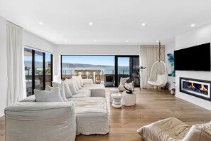 A modern living room with a large sofa set, a fireplace, and a view of the sea. - 9 Oceania (Lorne)