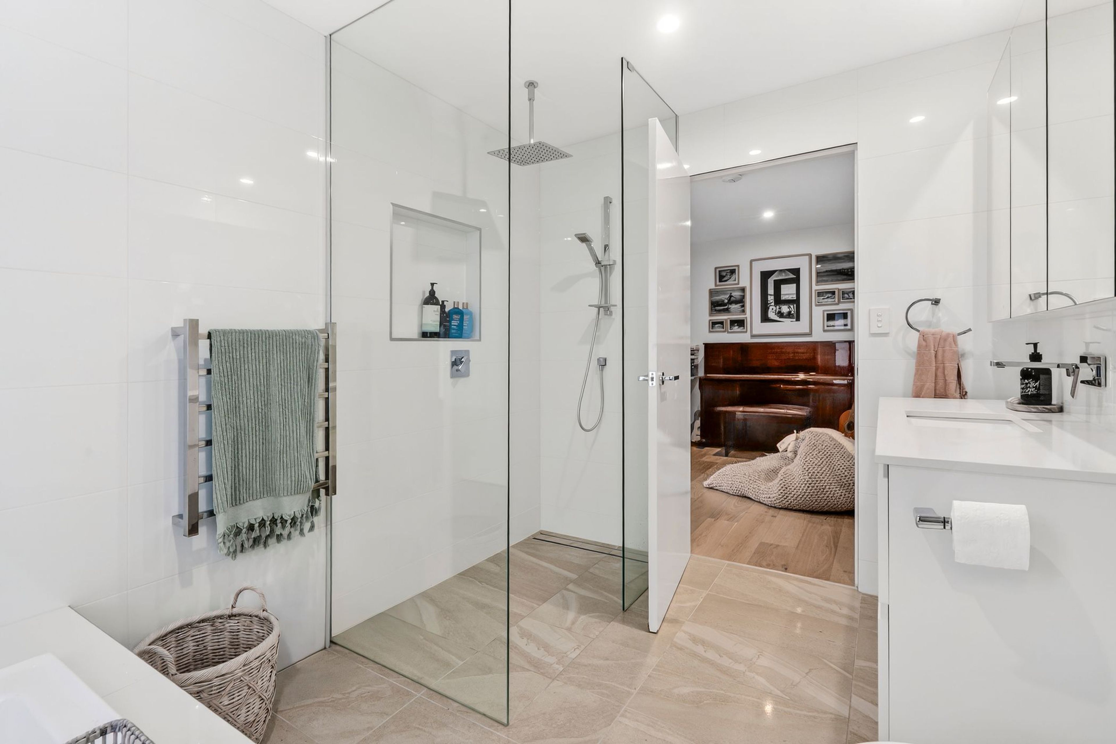 A modern bathroom with a glass shower enclosure, a white sink, and a mirror.
