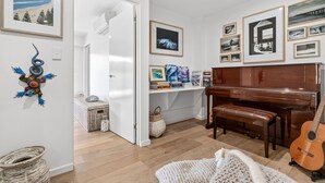 A room with a piano, a guitar, and various framed pictures on the walls. - 9 Oceania (Lorne)