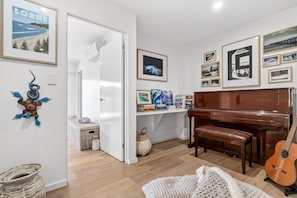 A room with a piano, a guitar, and various framed pictures on the walls. - 9 Oceania (Lorne)