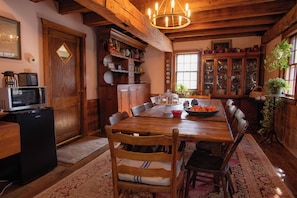 A wooden dining room with a large table, chairs, a refrigerator, and a microwave. - Historic 1849 Grist Mill House, Sleeps 9, Blue Ridge Parkway (Vesuvius)