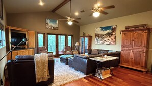 A spacious living room with hardwood floors, a fireplace, a large sofa, and a dining area. - Hill Country Escape near Wineries, Mae’s Ridge Wedding Venue & P. Falls State Pk (Johnson City)