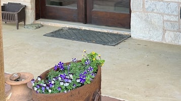 A wooden door with a keypad lock, a stone planter with flowers, and a bench outside a building.
