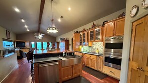 A spacious kitchen with wooden cabinets, a stainless steel dishwasher, and a large island. - Hill Country Escape near Wineries, Mae’s Ridge Wedding Venue & P. Falls State Pk (Johnson City)
