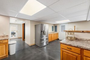 A modern kitchen with a stainless steel refrigerator, wooden cabinets, granite countertops, and a skylight. - Mt Rushmore Duplex  Retreat (Rapid City)