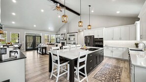 A modern kitchen with a central island, white cabinetry, and pendant lighting.