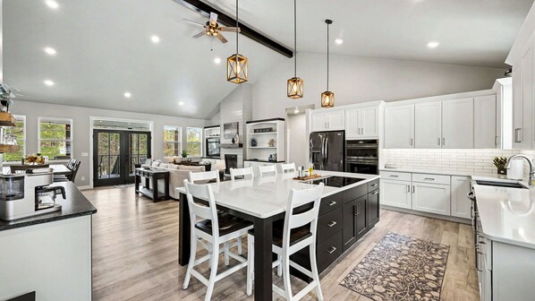 A modern kitchen with a central island, white cabinetry, and pendant lighting.