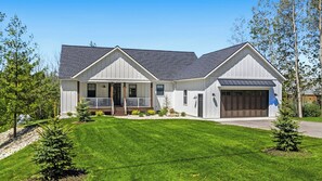 A two-story house with a front porch, a garage, and a well-maintained lawn.