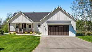 A two-story house with a front porch, a garage, and a well-maintained lawn. - Walk to Sister Bay! Fireplace, Ping Pong & Patio (Sister Bay)