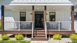 A two-story building with a covered porch, a front door, and a staircase leading to the entrance.