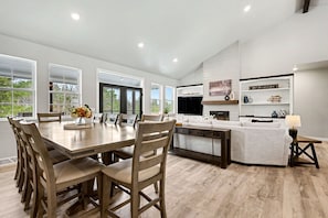A modern kitchen with a dining area, large windows, and a built-in TV.