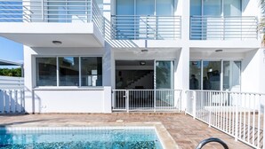 Un bâtiment moderne doté d’une piscine, de grandes fenêtres et d’une façade blanche.