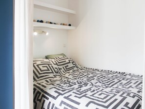 A bedroom with a bed, a pillow, a ceiling fan, and a shelf with decorative items. - Bright 30m² near Père Lachaise, Paris (Paris)