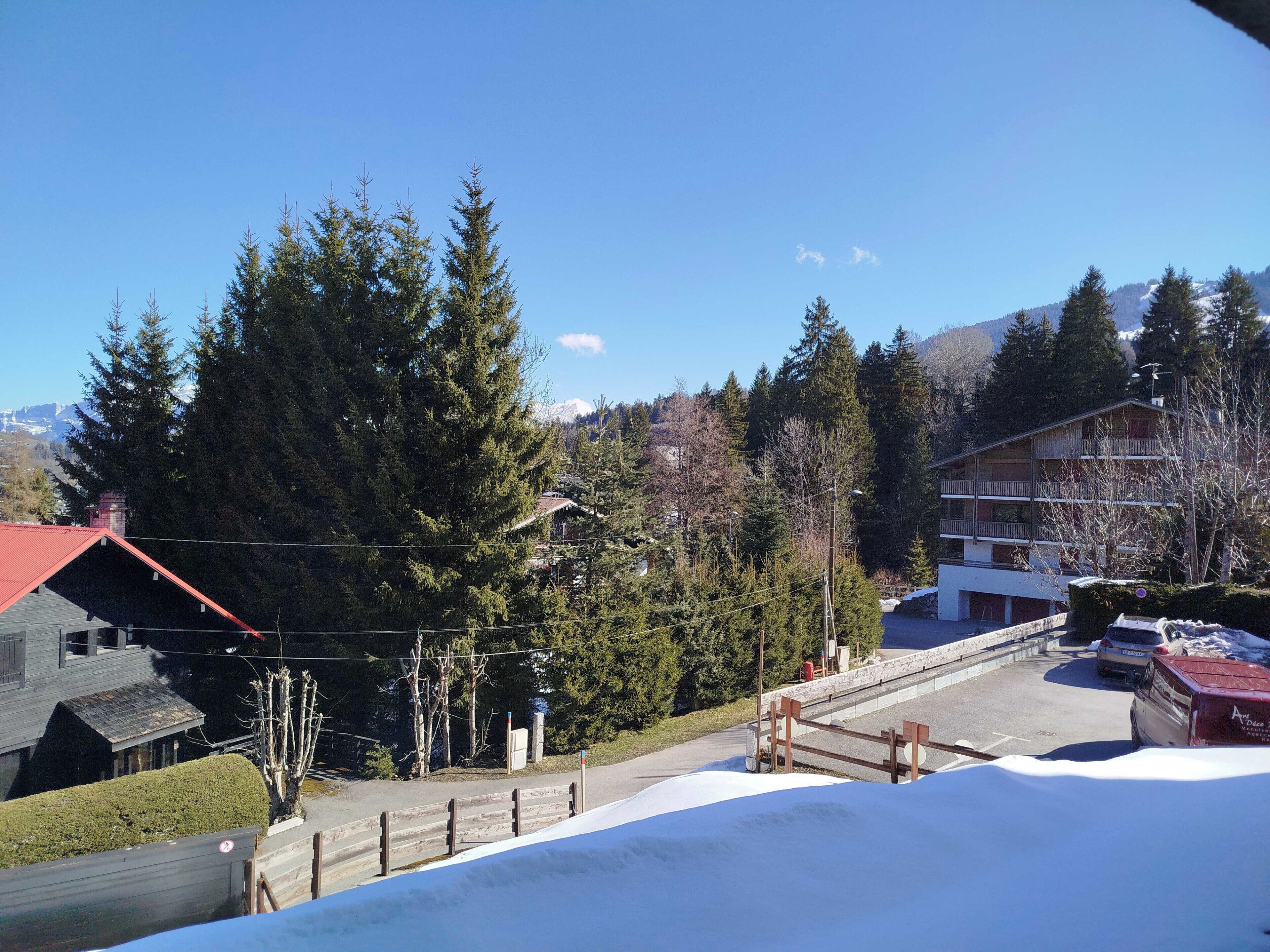 Zona residencial amb un edifici de teulada vermella, una àrea de pàrquing i terra coberta de neu.