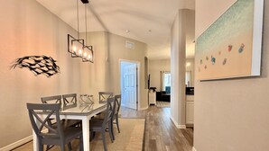 Un comedor con una mesa y sillas, una lámpara colgante y una puerta que da a otra habitación.