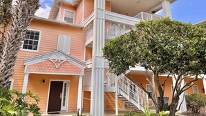 Un edificio de varios pisos con un balcón, una puerta y una escalera.