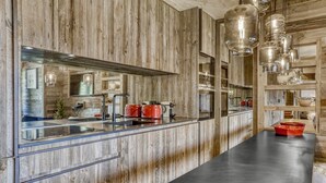Una cucina con rivestimenti in legno, un piano di lavoro nero e lampade a sospensione.