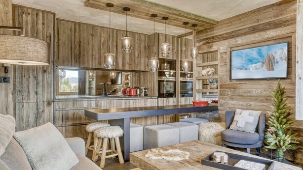 Una cucina moderna con elementi in legno, una zona bar e un'accogliente area salotto con divano e sgabelli.