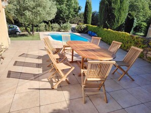 A patio with a pool, wooden furniture, and a hedge. - House in Rochefort with Private Pool & AC (Rochefort-du-Gard)