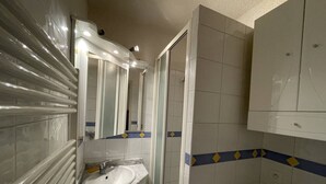 Un baño con lavamanos, espejo y paredes de azulejos.