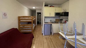 Una habitación con literas, un kitchenette pequeño y un sofá rojo.