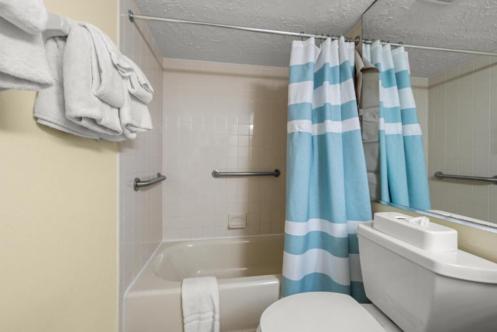 A bathroom with a bathtub, toilet, and a shower curtain.