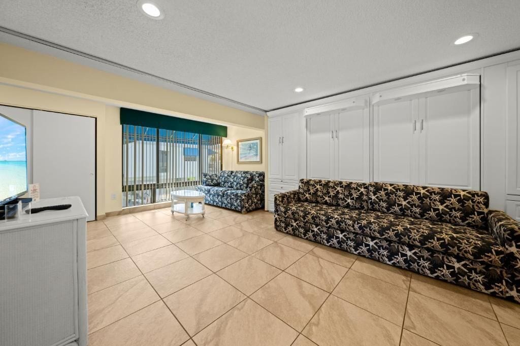 A spacious living area with a sofa, a small table, and a TV on a cabinet.