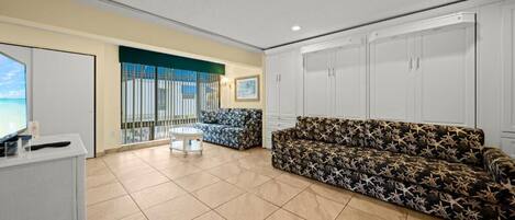 A spacious living area with a sofa, a small table, and a TV on a cabinet.