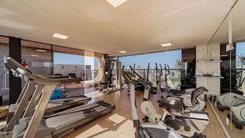 A gym with exercise equipment, large windows, and a view of the city.