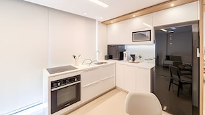 Une cuisine moderne équipée d’un lave-vaisselle, d’un four et d’un coin repas avec une table et des chaises en verre.