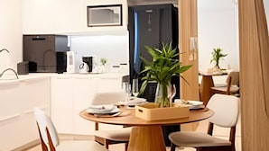 Une cuisine moderne avec des meubles blancs, un îlot central doté de chaises et un coin repas avec une table ronde et des chaises.