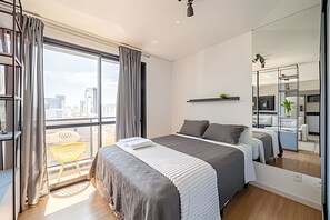 A modern bedroom with a large bed, a balcony with a chair, a small shelf, and a large mirror.
