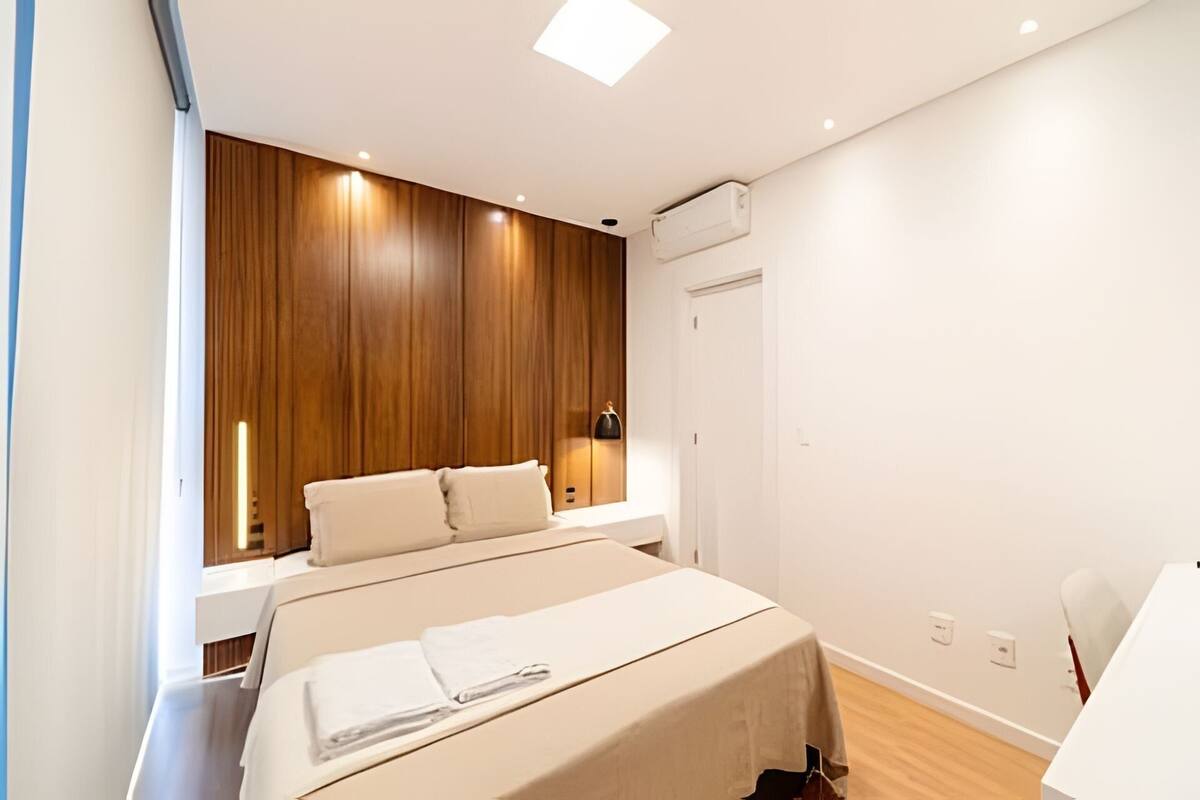 A bedroom with a bed, bedside tables, a wardrobe, and a door.