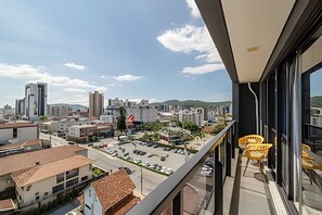 A balcony with a view of a cityscape, including buildings and a parking lot. - Flipchave - Apartamentos Highline design (Joinville)