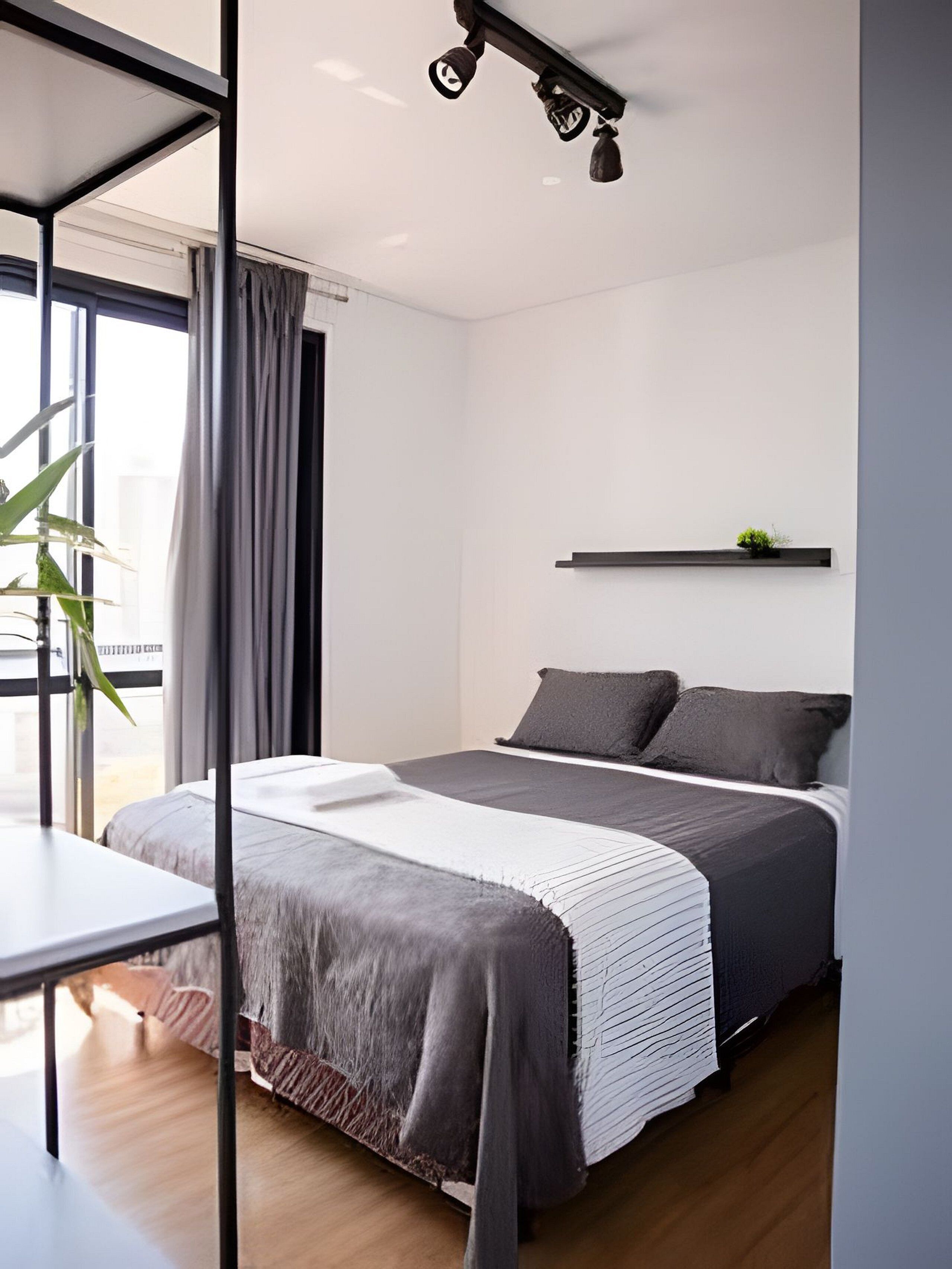 Een moderne slaapkamer met een bed, nachtkastje en raam met gordijnen.