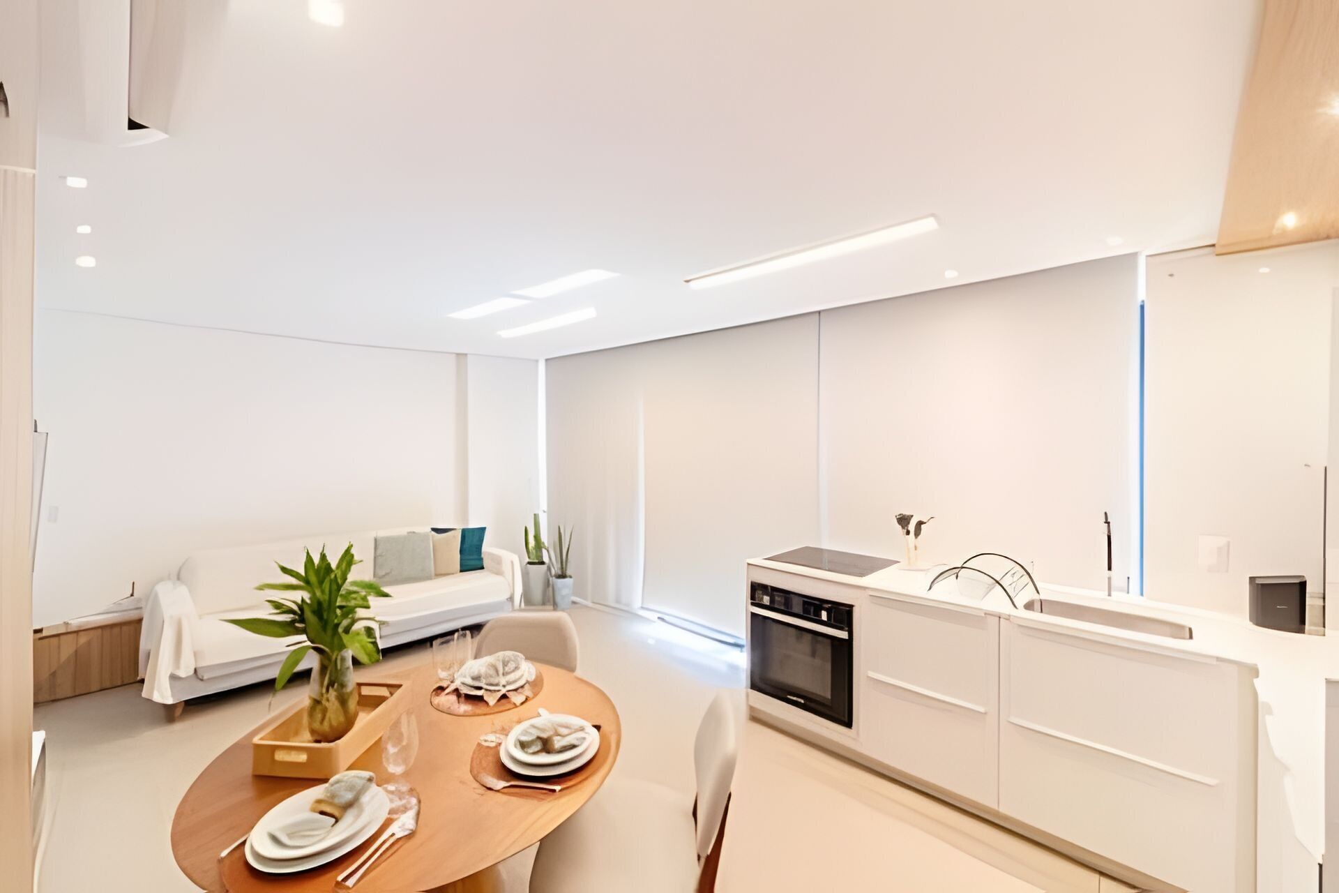 A modern kitchen with a dining area, white cabinetry, and a dining table set for two.
