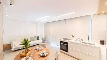 A modern kitchen with a dining area, white cabinetry, and a dining table set for two.