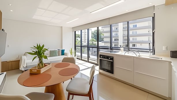 Une cuisine moderne avec un coin repas, de grandes fenêtres et une vue sur les immebles.