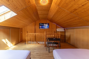 Ein Holzinnenraum mit einem Bett, einem Schreibtisch und einem Fernseher.