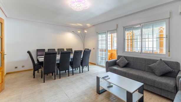 A modern living room with a dining area, a sofa, and a coffee table. - Semi-detached chalet for up to 12 guests, Pool, BBQ (Loeches)