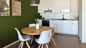 A modern kitchen with white cabinets, a wooden dining table, and a pendant light. - Modern comfort in the heart of Bocholt - Stylish apartment for up to 4 guests (Bocholt)