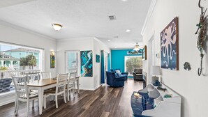 Un salon moderne avec un coin repas, un mur d’accent bleu et des œuvres d’art accrochées aux murs.