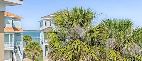 A coastal property with a clear view of the sea, a white building with a red roof, and lush greenery.