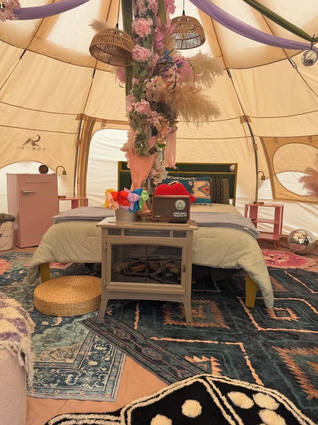 Een tent met een bed, een radio en een decoratieve hanglamp.