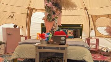 Een tent met een bed, een radio en een decoratieve hanglamp.